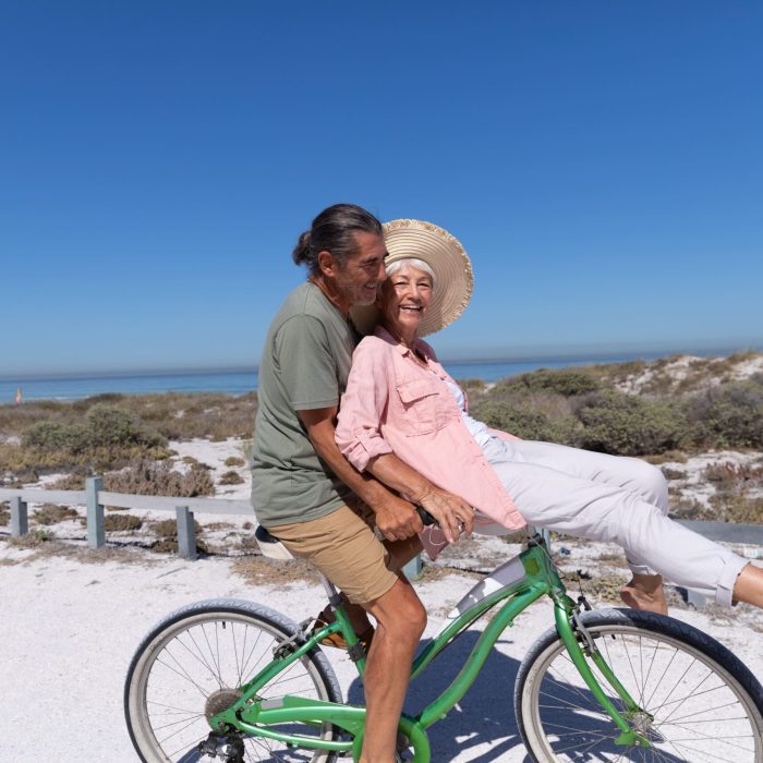 senior-caucasian-couple-riding-a-bike-at-the-beach-2021-08-28-16-52-05-utc